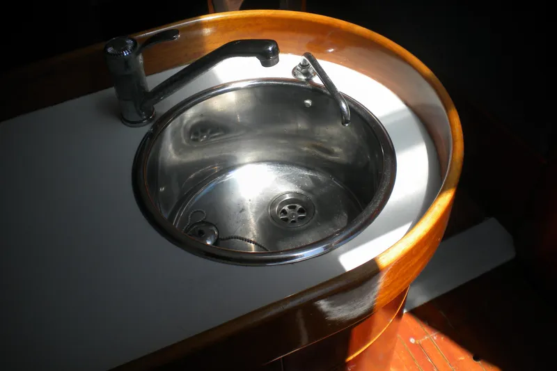 Slide: The Image of Stainless steel sink in 1994 Beneteau First 310 yacht, featuring wooden trim and modern faucet. - 23