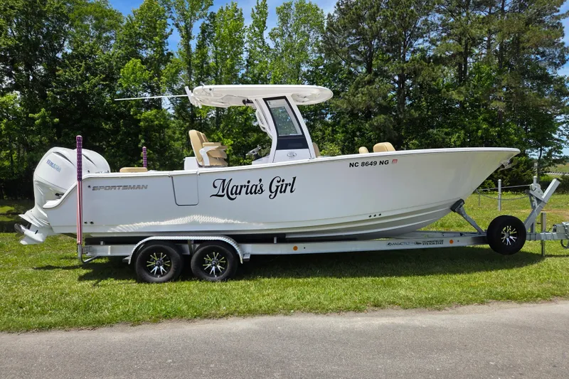 The Image of 2025 Sportsman Open 262 Center Console boat on trailer, named "Maria's Girl," in a grassy area. - 0