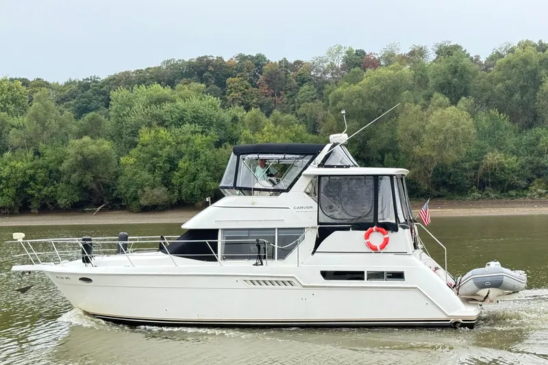 The Image of 1997 Carver 355 Aft Cabin Motor Yacht cruising on a river with lush green trees. - 0