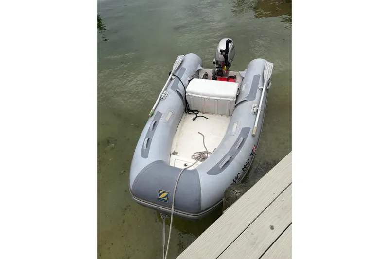 Slide: The Image of Inflatable dinghy with motor, docked on calm water near a wooden pier. - 49