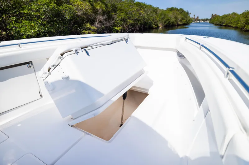 Slide: The Image of 2015 Invincible 39 Open Fisherman boat with open storage compartment, surrounded by lush greenery. - 19