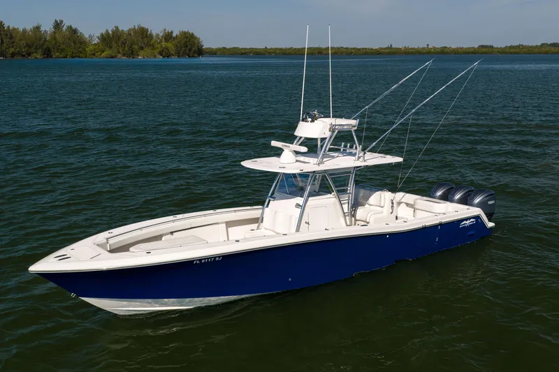Slide: The Image of 2015 Invincible 39 Open Fisherman boat on calm water, featuring a sleek blue and white design. - 2