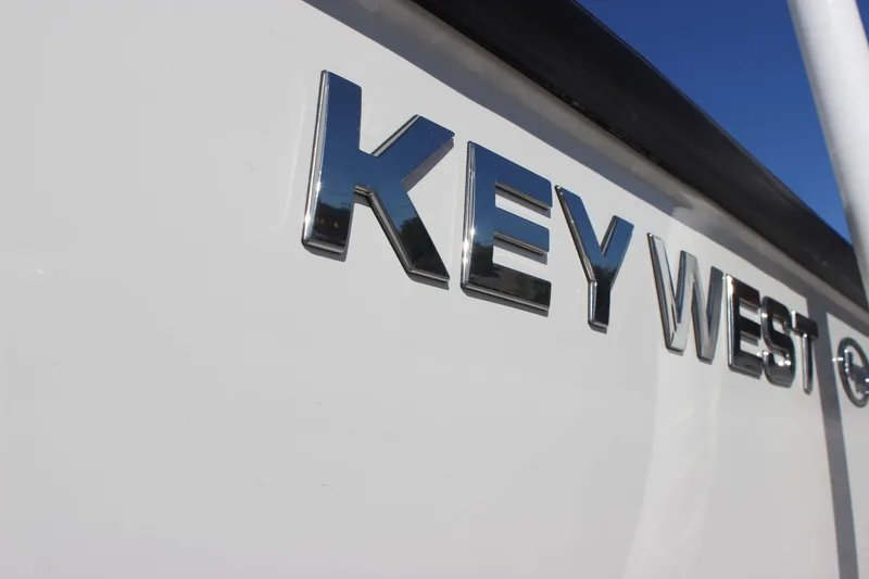 Slide: The Image of Key West 210 Bay Reef 2026 boat logo in shiny chrome letters on white surface. - 4