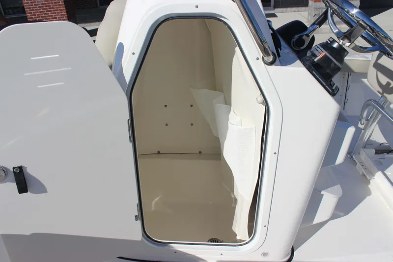 Slide: The Image of 2026 Key West 210 Bay Reef boat console storage area with open door. - 8