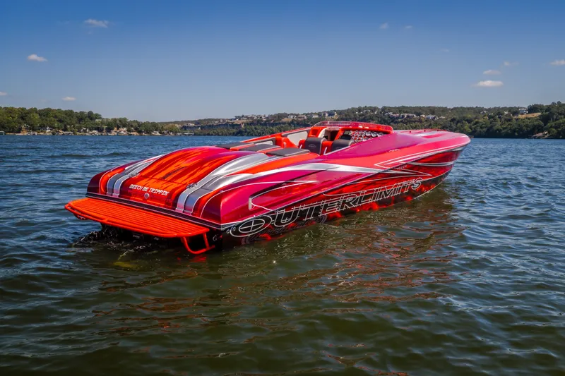 Slide: The Image of 2004 Outerlimits 42 Legacy speedboat with vibrant red and silver design on a sunny lake. - 43