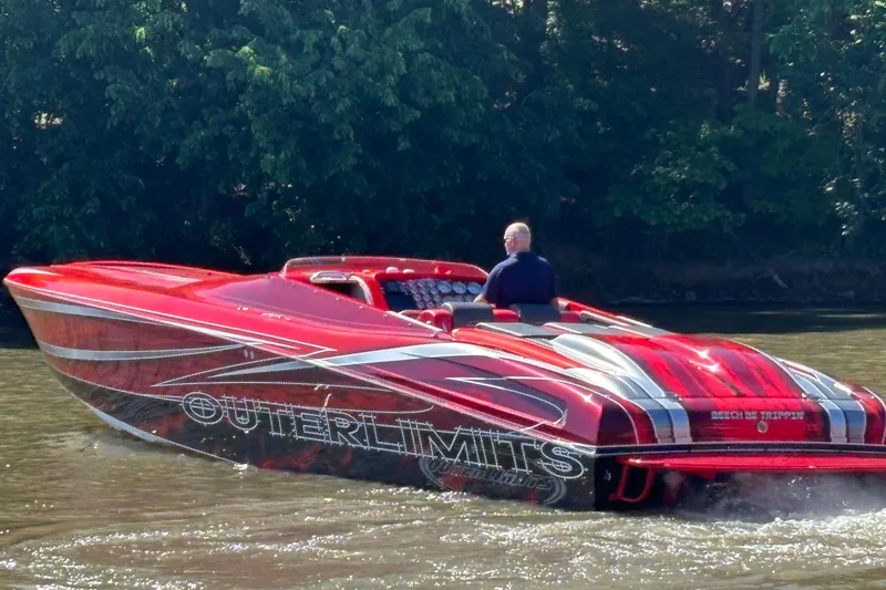 Slide: The Image of Red 2004 Outerlimits 42 Legacy speedboat cruising on a river with lush green trees. - 3