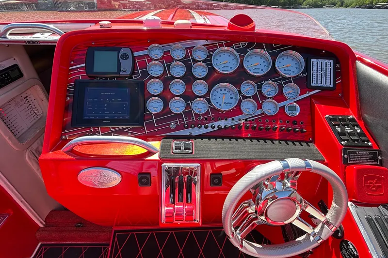 Slide: The Image of Red dashboard of 2004 Outerlimits 42 Legacy boat with gauges and steering wheel. - 36