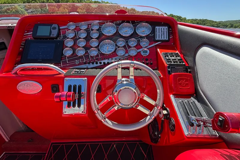 Slide: The Image of Red dashboard of a 2004 Outerlimits 42 Legacy boat with gauges and steering wheel. - 46