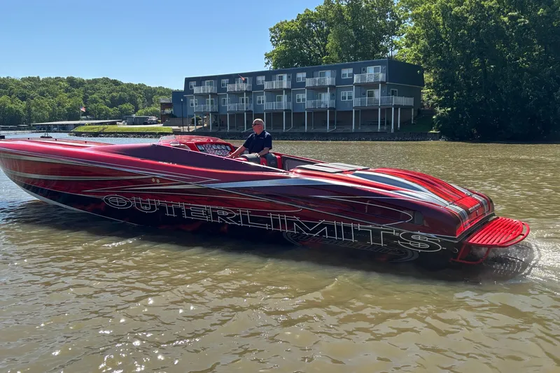 Slide: The Image of 2004 Outerlimits 42 Legacy speedboat on a river, vibrant red design, near modern buildings. - 6