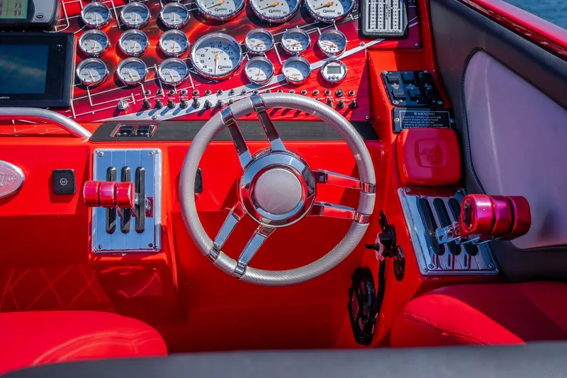 Slide: The Image of Red dashboard of a 2004 Outerlimits 42 Legacy boat with gauges and steering wheel. - 23