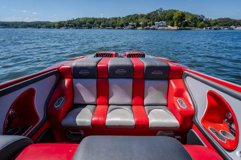 Slide: The Image of 2004 Outerlimits 42 Legacy boat interior with red and gray seating on a scenic lake. - 20