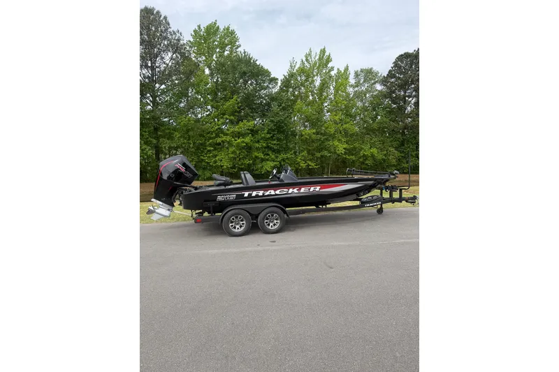 The Image of 2025 Tracker Savage 215 boat on trailer, parked on road with trees in background. - 1