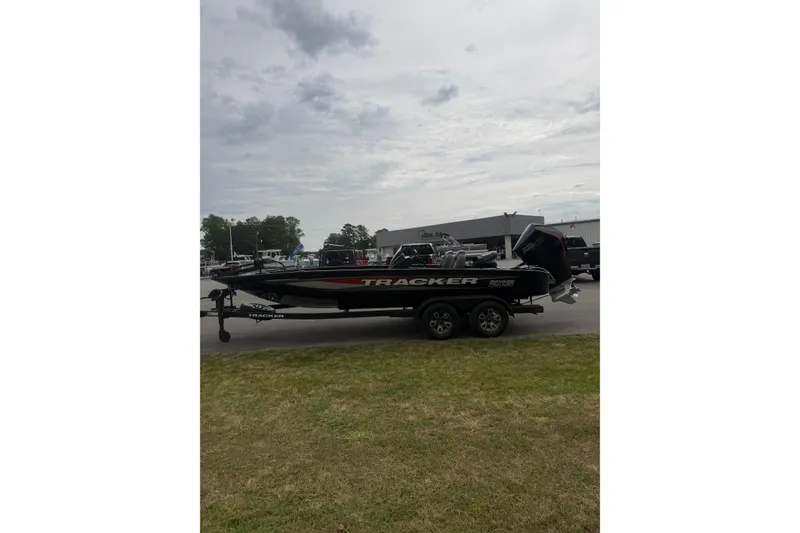 Slide: The Image of 2025 Tracker Savage 215 boat on trailer in parking lot, cloudy sky background. - 3
