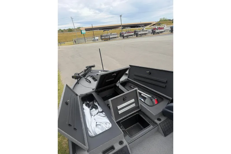 Slide: The Image of 2025 Tracker Savage 215 boat interior with open storage compartments in a parking lot. - 6