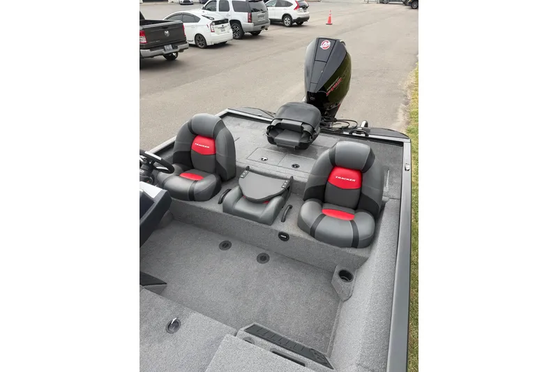 Slide: The Image of 2025 Tracker Savage 215 boat interior with dual seats and motor in parking lot. - 7