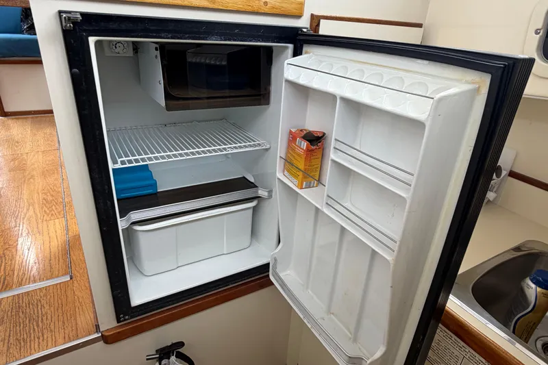 Slide: The Image of Open refrigerator inside 2005 Camano Trawler boat, showing shelves and a carton. - 11