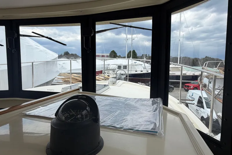 Slide: The Image of Interior view of 2005 Camano Trawler with compass, overlooking marina and parked vehicles. - 15