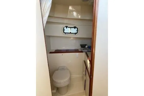 Slide: The Image of 2005 Camano Trawler bathroom interior with toilet, window, and storage shelf. - 17