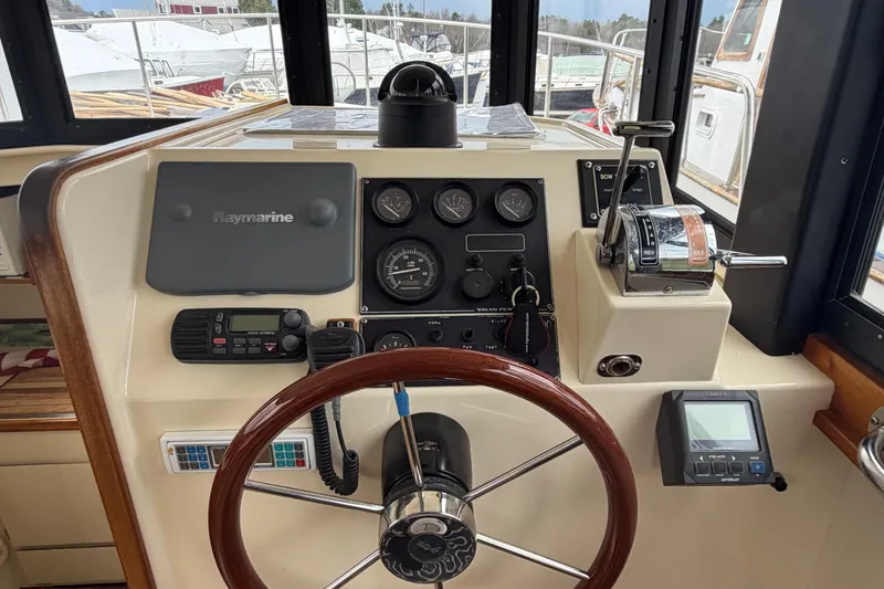 Slide: The Image of 2005 Camano Trawler helm with Raymarine navigation, gauges, and wooden steering wheel. - 2