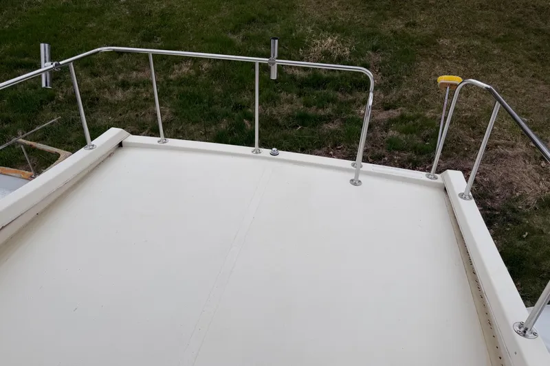 Slide: The Image of 2005 Camano Trawler deck with stainless steel railings, grassy background. - 30