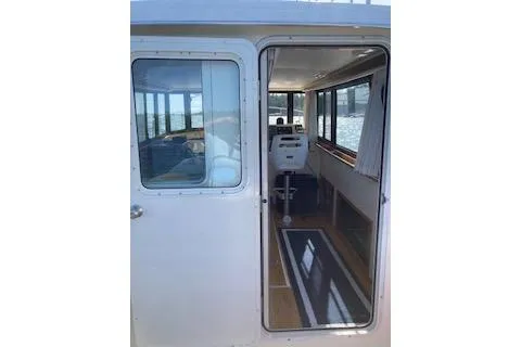 Slide: The Image of 2005 Camano Trawler interior view through open door, showcasing helm and seating area. - 33