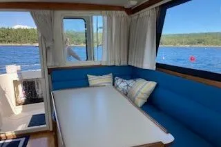 Slide: The Image of Interior of 2005 Camano Trawler with blue seating, table, and scenic water view. - 4