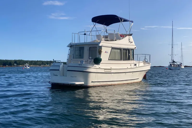 Slide: The Image of 1999 Camano Trawler boat anchored on calm water under a clear blue sky. - 40