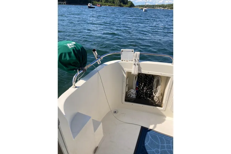 Slide: The Image of 1999 Camano Trawler boat deck with storage compartment, ropes, and scenic water view. - 41