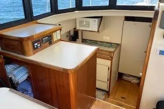 Slide: The Image of 2005 Camano Trawler interior with wood cabinetry, compact kitchen, and ocean view. - 5
