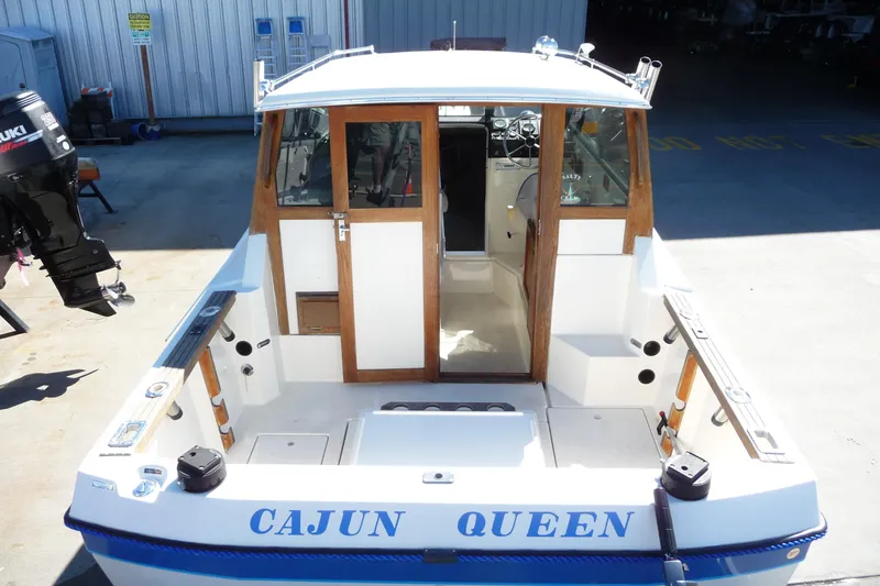 Slide: The Image of 1988 Bayliner 2102 Trophy boat, rear view, docked with visible Suzuki outboard motor. - 13