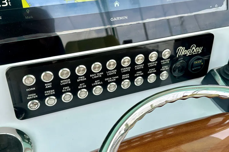 Slide: The Image of Control panel of a 2020 Mag Bay 33 CC boat with labeled buttons and Garmin display. - 13
