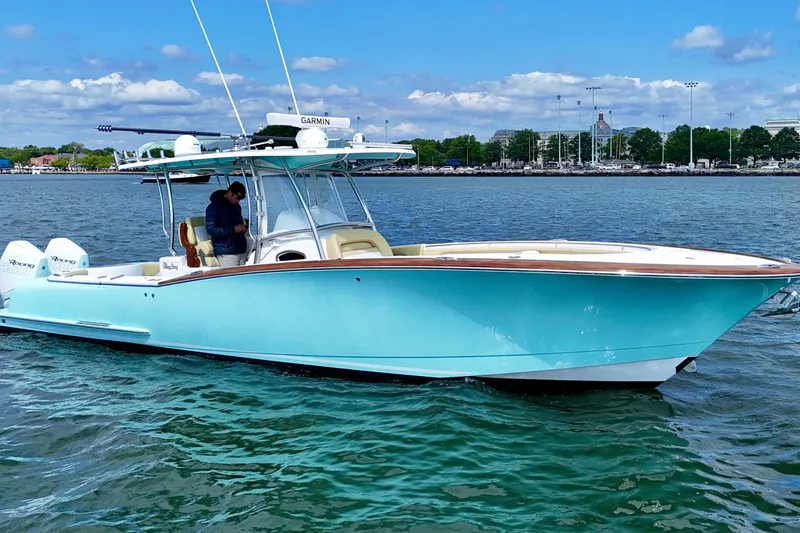 Slide: The Image of 2020 Mag Bay 33 CC boat on water, featuring sleek design and vibrant blue hull. - 2