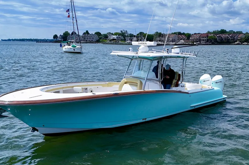 Slide: The Image of 2020 Mag Bay 33 CC boat on water, featuring sleek design and vibrant blue hull. - 6