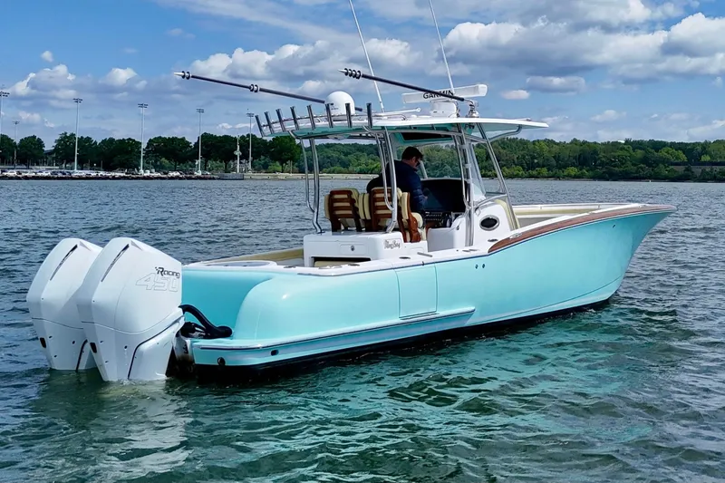 Slide: The Image of 2020 Mag Bay 33 CC boat on water with twin engines, clear sky, and lush shoreline. - 7