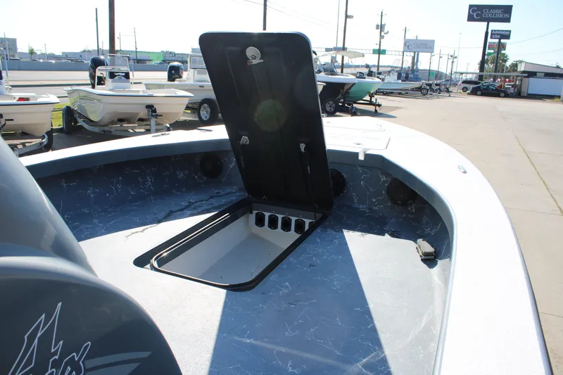 Slide: The Image of 2023 Mamba 24VX boat with open storage compartment, displayed in a dealership lot. - 18