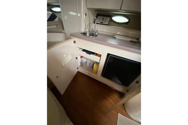 Slide: The Image of Compact kitchen area in a 1995 Regal Commodore 322 boat, featuring a sink and storage. - 21