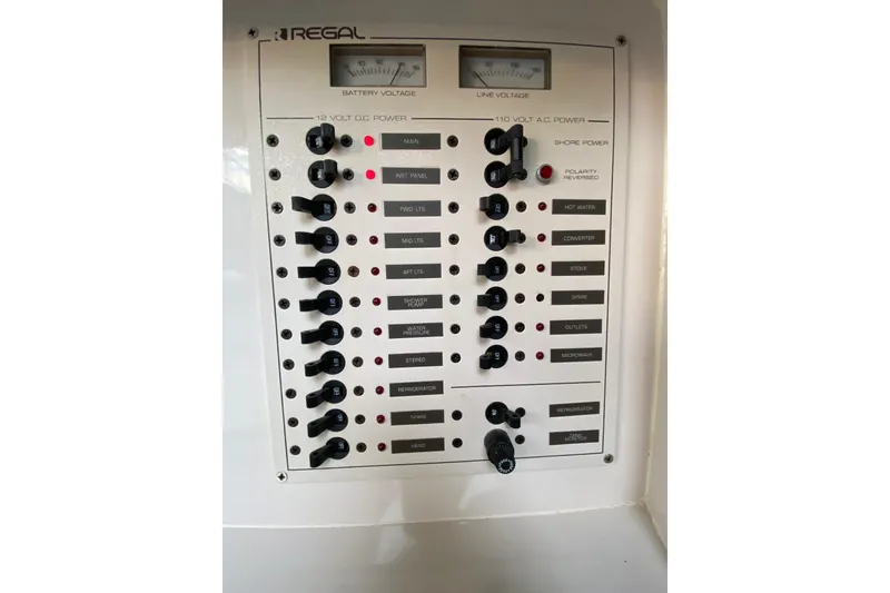 Slide: The Image of Control panel of a 1995 Regal Commodore 322 boat, featuring voltage meters and switches. - 23