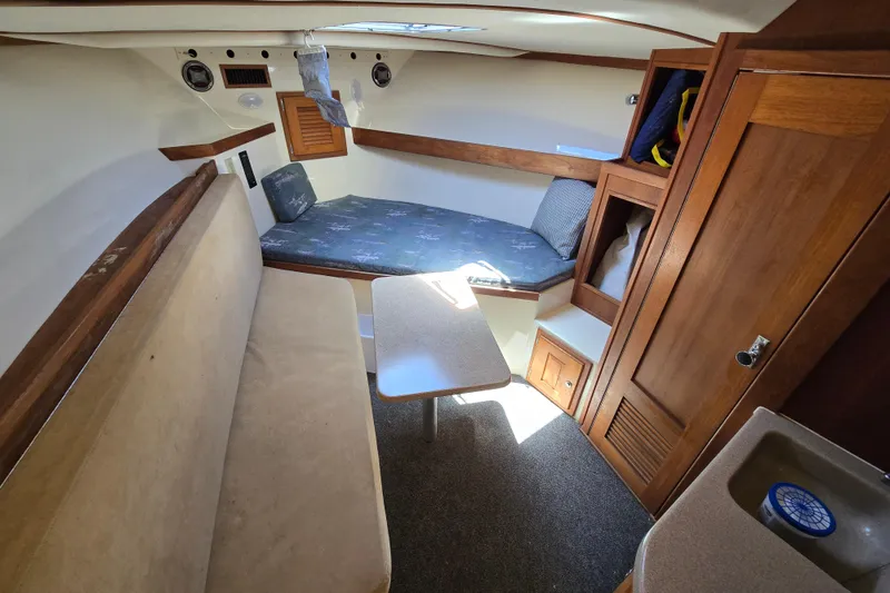 Slide: The Image of 2003 Albemarle 305 Express Fisherman cabin interior with seating, table, and wooden storage. - 23