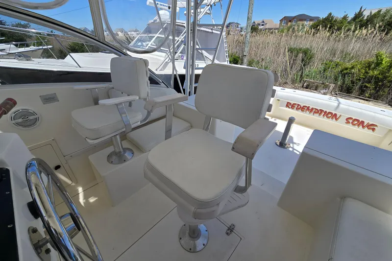 Slide: The Image of 2003 Albemarle 305 Express Fisherman boat interior with white captain chairs and steering wheel. - 8