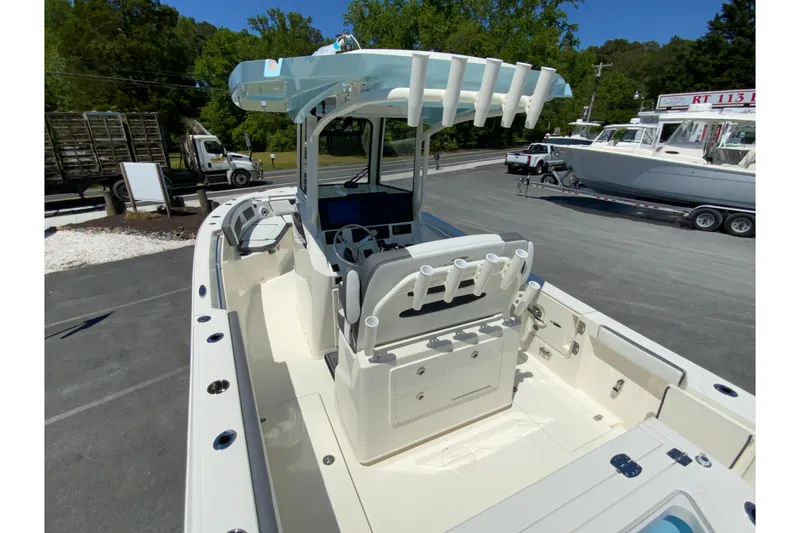 Slide: The Image of 2026 Cobia 245 Center Console boat with T-top and rod holders in a parking lot. - 12