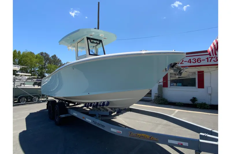 Slide: The Image of 2026 Cobia 245 Center Console boat on trailer, parked outdoors under clear blue sky. - 3