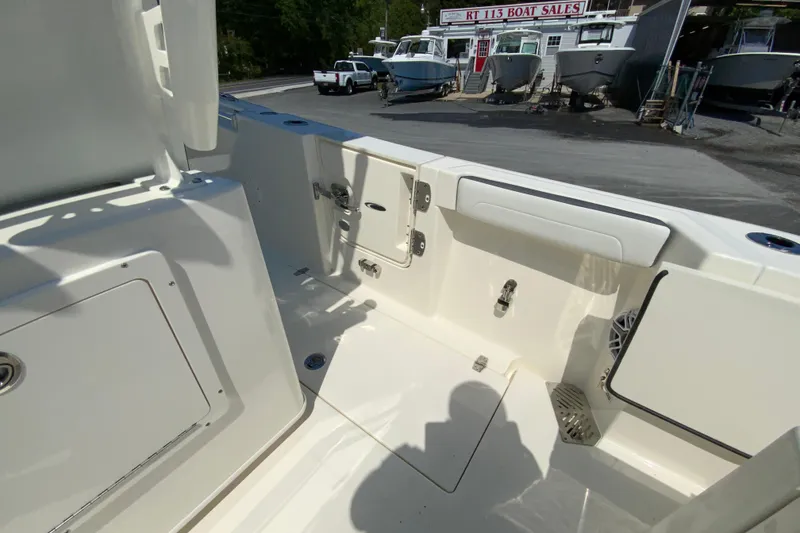 Slide: The Image of 2026 Cobia 245 Center Console boat interior at dealership, showcasing seating and storage compartments. - 40