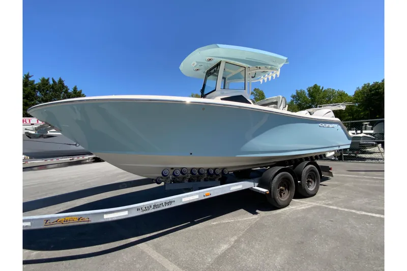 Slide: The Image of 2026 Cobia 245 Center Console boat on trailer, displayed outdoors under clear blue sky. - 6