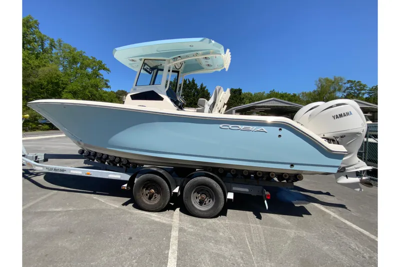 Slide: The Image of 2026 Cobia 245 Center Console boat on trailer, featuring Yamaha engine, parked outdoors. - 7