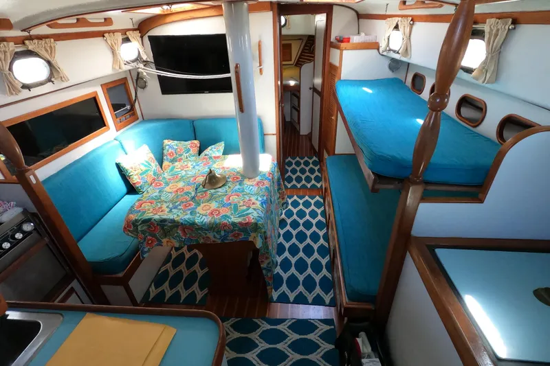 Slide: The Image of Interior of a 1978 CSY 44 sailboat with vibrant blue seating and floral tablecloth. - 12