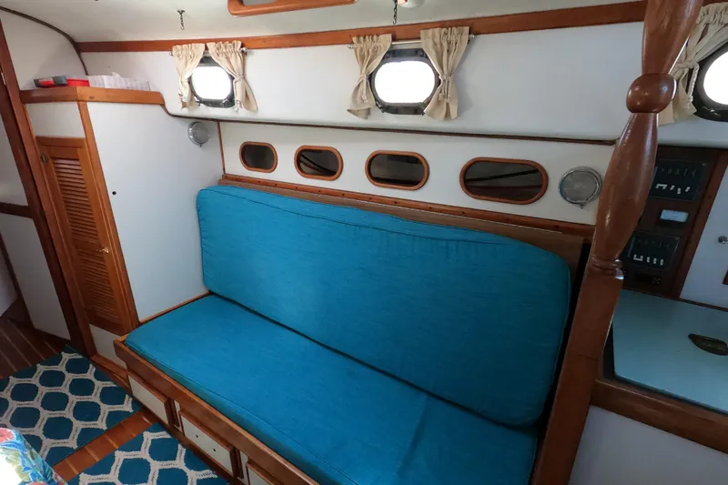 Slide: The Image of 1978 CSY 44 yacht interior with blue cushioned seating and wooden accents. - 14