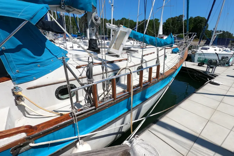 Slide: The Image of 1978 CSY 44 sailboat docked, featuring blue and white design with wooden accents. - 2