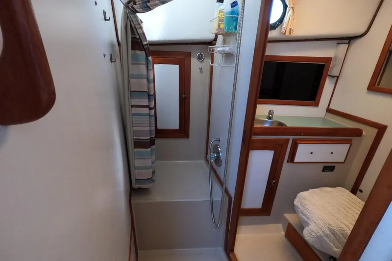 Slide: The Image of 1978 CSY 44 yacht bathroom with shower, sink, and wooden accents. - 23