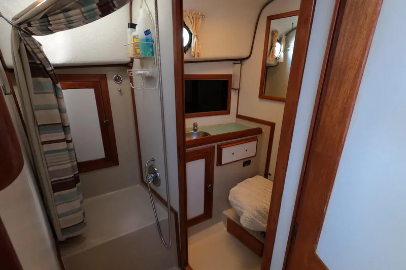 Slide: The Image of 1978 CSY 44 yacht bathroom with shower, sink, and wooden accents. - 24