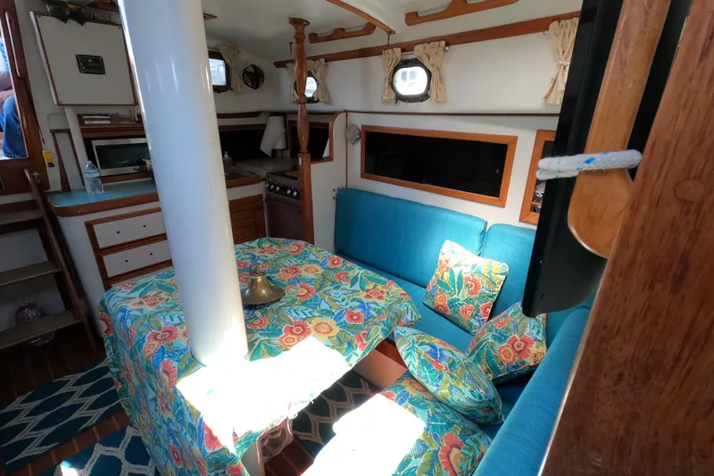 Slide: The Image of Interior of a 1978 CSY 44 sailboat with vibrant floral decor and blue seating. - 27